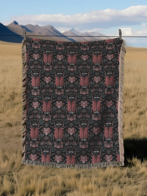 Luxurious woven cotton throw blanket featuring symmetrical scarab beetle pattern in terracotta on black background with white fringe detail. Perfect as gothic wall tapestry, dark academia decor, or cottagecore blanket for bedroom or living room.